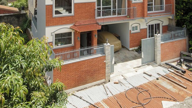 A multi-story residential building with balconies, large windows, and a brick facade.