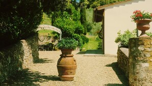 Un sendero de grava que conduce a una edificación rústica con muros de piedra y una puerta.
