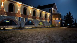 A building with multiple arched windows and a stone facade at night. - Winery Chabiant Hotel (Ismailli)