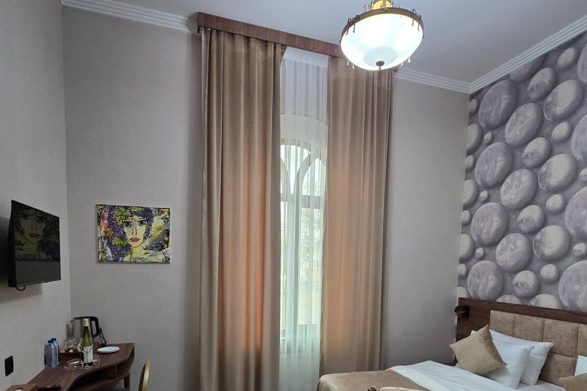 Ein Hotelzimmer mit Bett, Schreibtisch, Stuhl, Fernseher und einem Gemälde an der Wand.