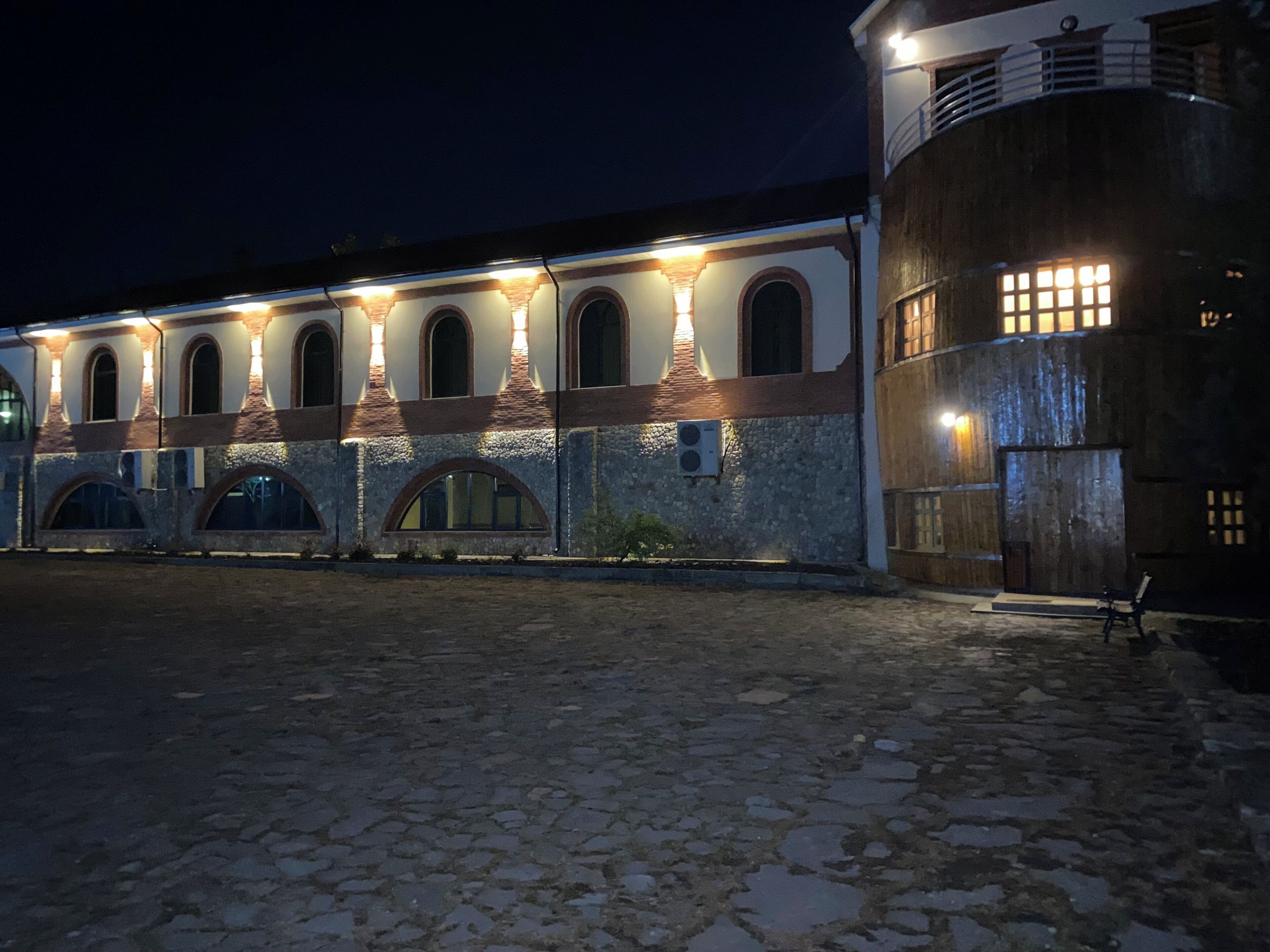 Ein Gebäude mit Rundbogenfenstern und einer Steinfassade bei Nacht.
