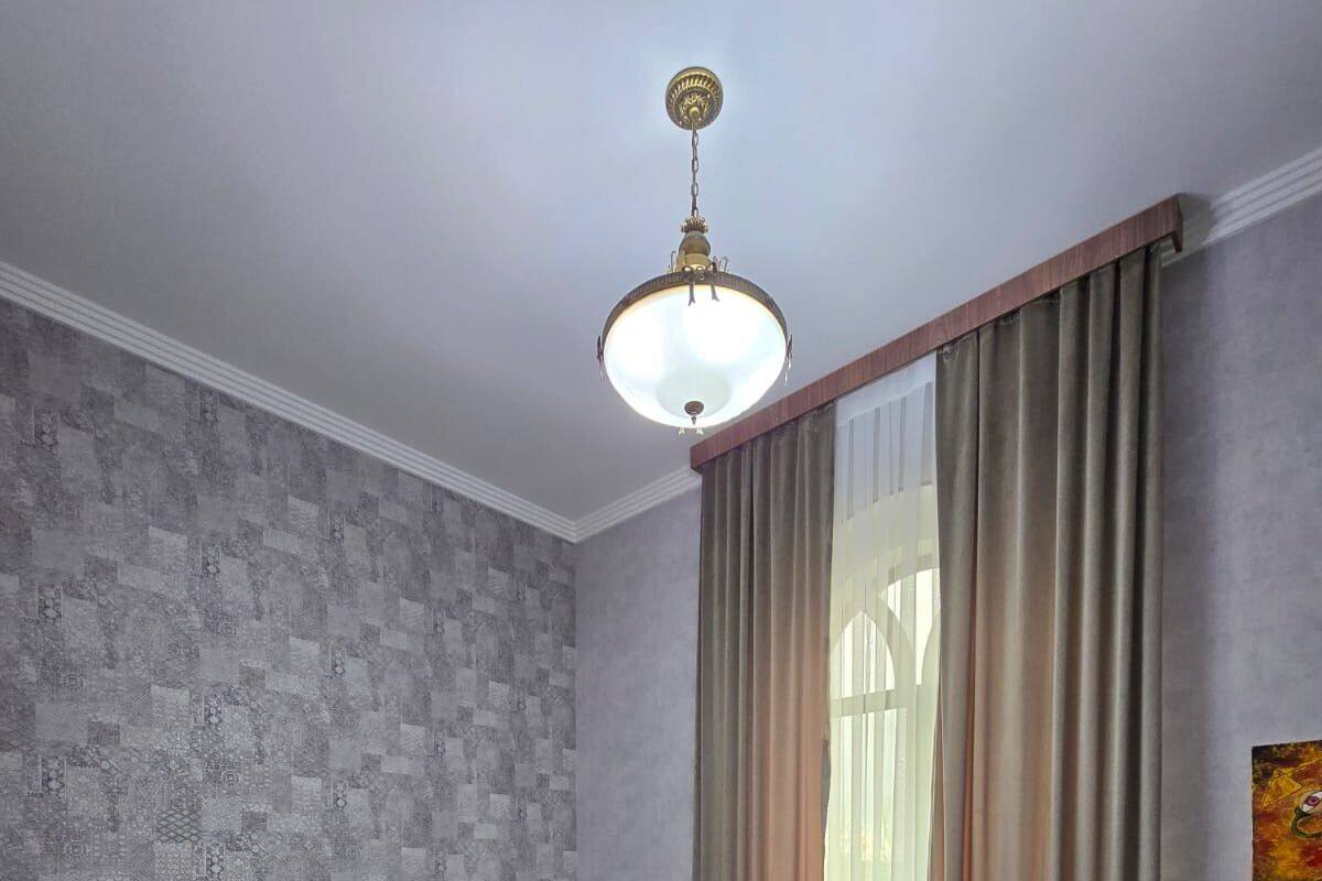 Ein Hotelzimmer mit zwei Betten, einer Wand mit Muster, einem grünen Teppich und einem großen Fenster mit Vorhängen.