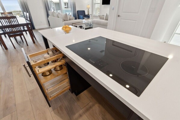 Una cocina moderna con placa de inducción integrada, armarios de madera y un comedor con vistas.