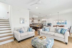 Ein modernes Wohnzimmer mit zwei Sofas, einem Couchtisch, einer Treppe und einer Küche im Hintergrund.