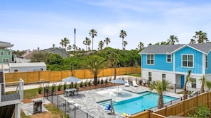 Un jardin à l’arrière d’une maison, avec une piscine, du mobilier de jardin et une clôture en bois.