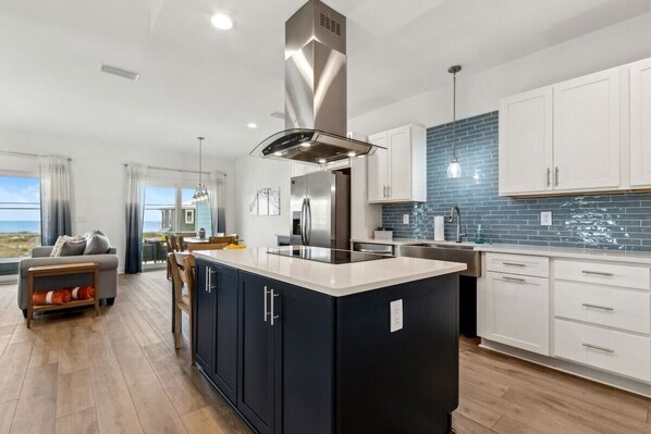 Una cocina moderna con una isla central, armarios blancos y salpicadero azul.