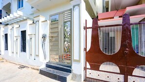 A residential building with a gated entrance, a staircase leading to the entrance, and a balcony with railings. - Aditya GH (Varanasi)