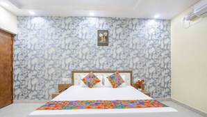 A bedroom with a marble-patterned wall, a bed with a colorful geometric bedspread, and a small framed picture above the bed. - Aditya GH (Varanasi)