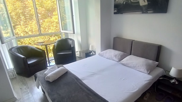 Une chambre à coucher avec un lit, une chaise, une table, une fenêtre et un tableau.