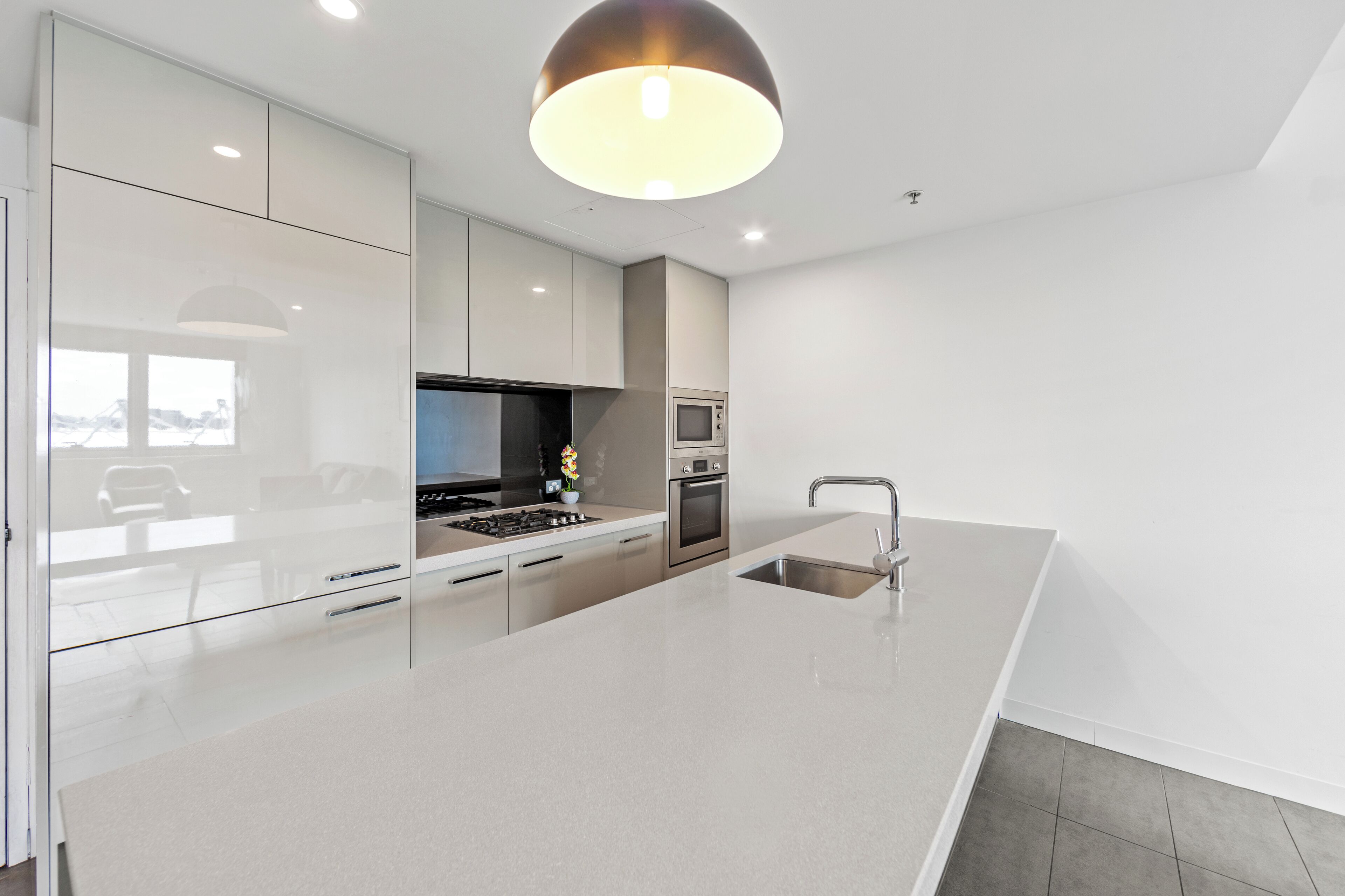 Een moderne keuken met een groot eiland, roestvrijstalen apparatuur en een hanglamp.