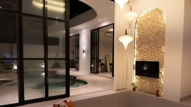 A modern interior with a pool, a flat-screen TV mounted on a textured wall, and a seating area with cushions. - Azure Luxe Private Pool Villa, 6min PererenanBeach (Pererenan)