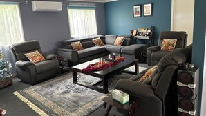 Una sala de estar moderna con un sofá seccional, un sillón reclinable, una mesa de centro y una mesita auxiliar.