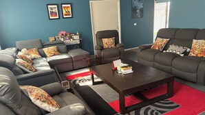 Una sala de estar con sofás grises, una mesa de centro y un tapete rojo y negro.