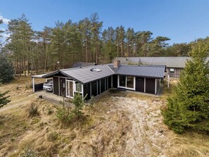 Une maison moderne avec un toit en pente, de grandes fenêtres et une véranda couverte.
