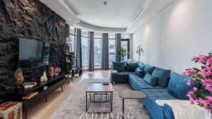 A modern living room with a large flat-screen TV, a blue sofa, and a stone accent wall.