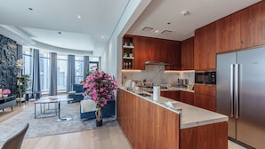 A modern kitchen with wooden cabinets, a Bosch refrigerator, and a marble countertop.
