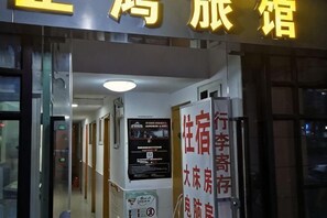 L’entrée d’un hôtel, avec une enseigne indiquant la présence d’une grande salle et d’une salle équipée d’un téléviseur.