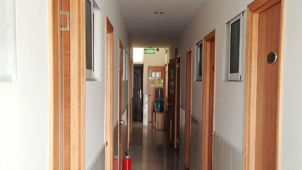 Un pasillo con puertas de madera, un extintor y una señal de salida visible.