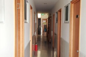 A hallway with wooden doors, a fire extinguisher, and a visible exit sign.