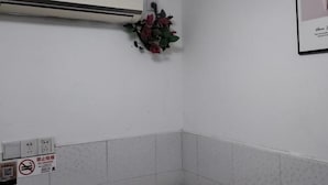 Un baño con un aire acondicionado blanco, un cartel de no fumar y un cuadro en la pared.