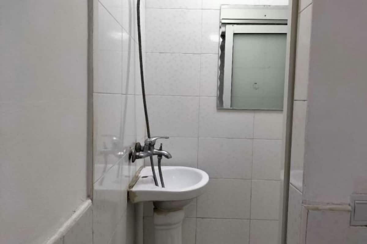 Une salle de bain avec un lavabo blanc, un miroir et un espace douche.