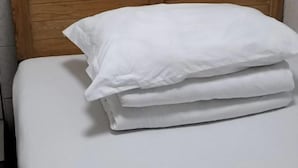 Una cama bien hecha con ropa de cama y almohadas blancas.