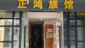 Entrada de un hotel con un letrero que dice "正鸿旅馆" (Zheng Hong Travel Inn).