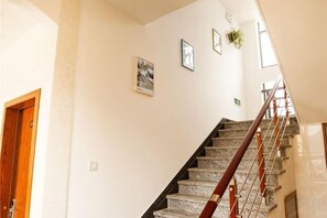 A staircase with a wooden handrail and a white wall with framed pictures. - Shengsi Haiyi Lanting Homestay (Shengsi)
