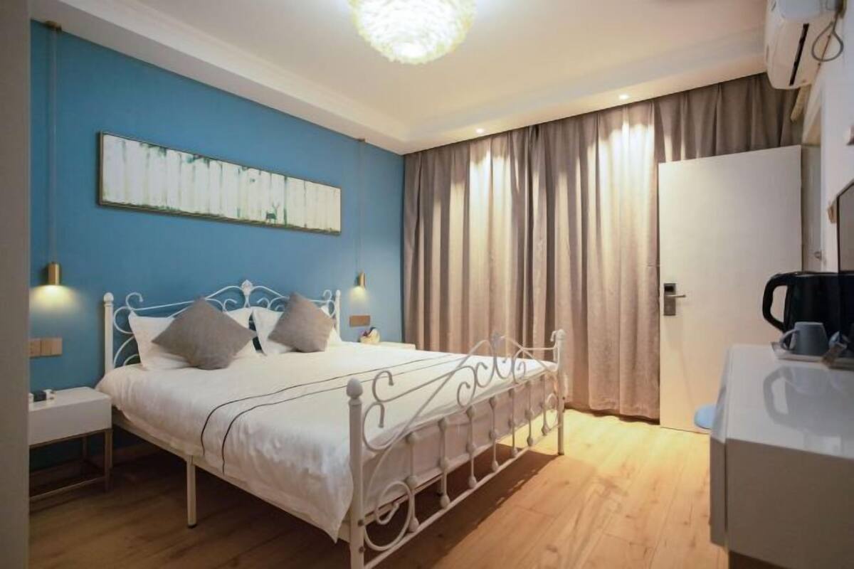 A bedroom with a bed, bedside tables, a wardrobe, and a painting on the wall.