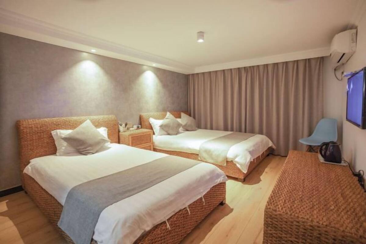 A hotel room with two beds, a TV, and a desk.