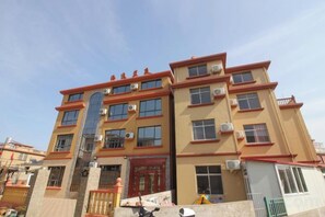 Un edificio de varios pisos con una puerta roja y múltiples ventanas.