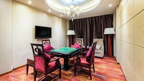 Une pièce comprenant une table de billard, quatre chaises, un téléviseur et un lustre.