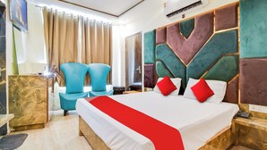 A hotel room with a large bed, two blue chairs, a marble accent wall, and a modern design. - Hotel Double Rr Newly Renovated  (New Delhi)