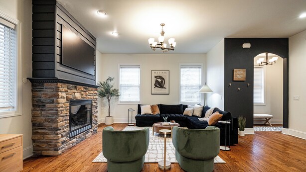 A living room with a stone fireplace, a black entertainment unit, a black sofa set, and a chandelier. - 1 Mile to Downtown -Brewers Hill-Rooftop Deck-Gym (Milwaukee)