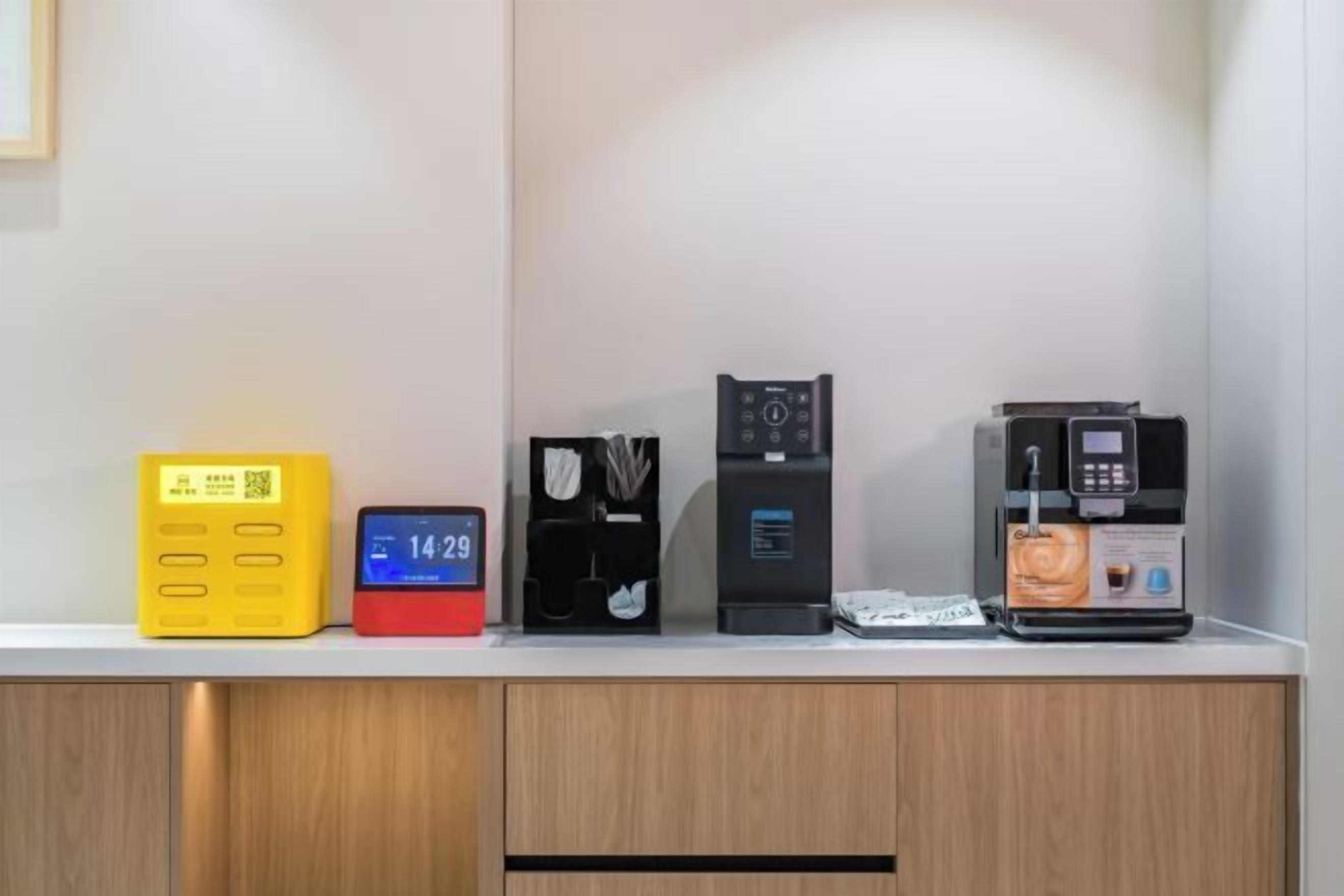 Una hilera de electrodomésticos sobre una encimera, incluyendo un aparato amarillo, un reloj digital rojo, una cafetera negra y una máquina de espresso negra.
