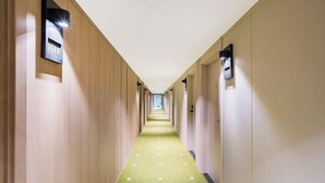 A hotel hallway with a green carpet and wooden walls. - Beijing ZhongKuang Hotel (Beijing)
