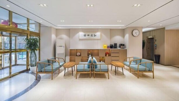 A modern hotel lobby with a reception desk, seating area with sofas and chairs, a clock, and a large window. - Beijing ZhongKuang Hotel (Beijing)