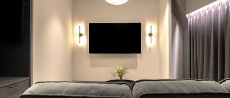 A modern living room with a flat-screen TV mounted on the wall, a sofa, and a pendant light.