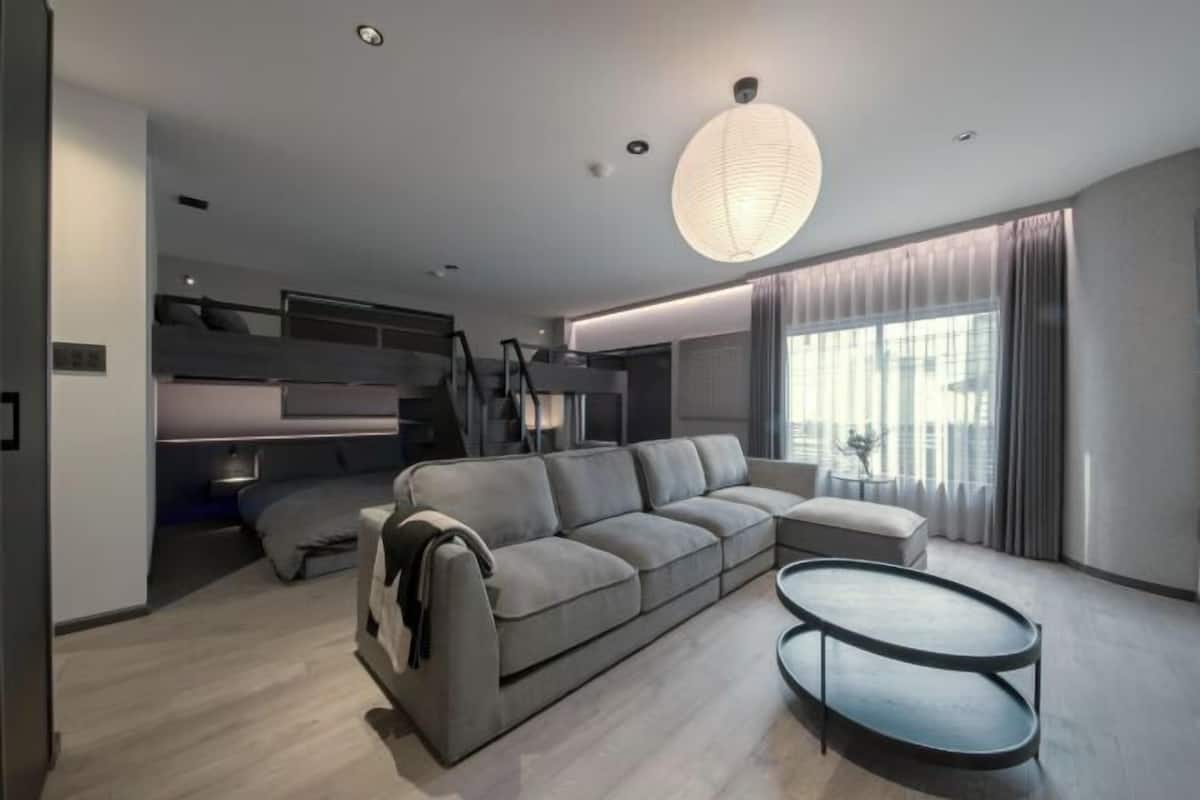A modern living room with a sectional sofa, a round coffee table, and a large window with curtains.