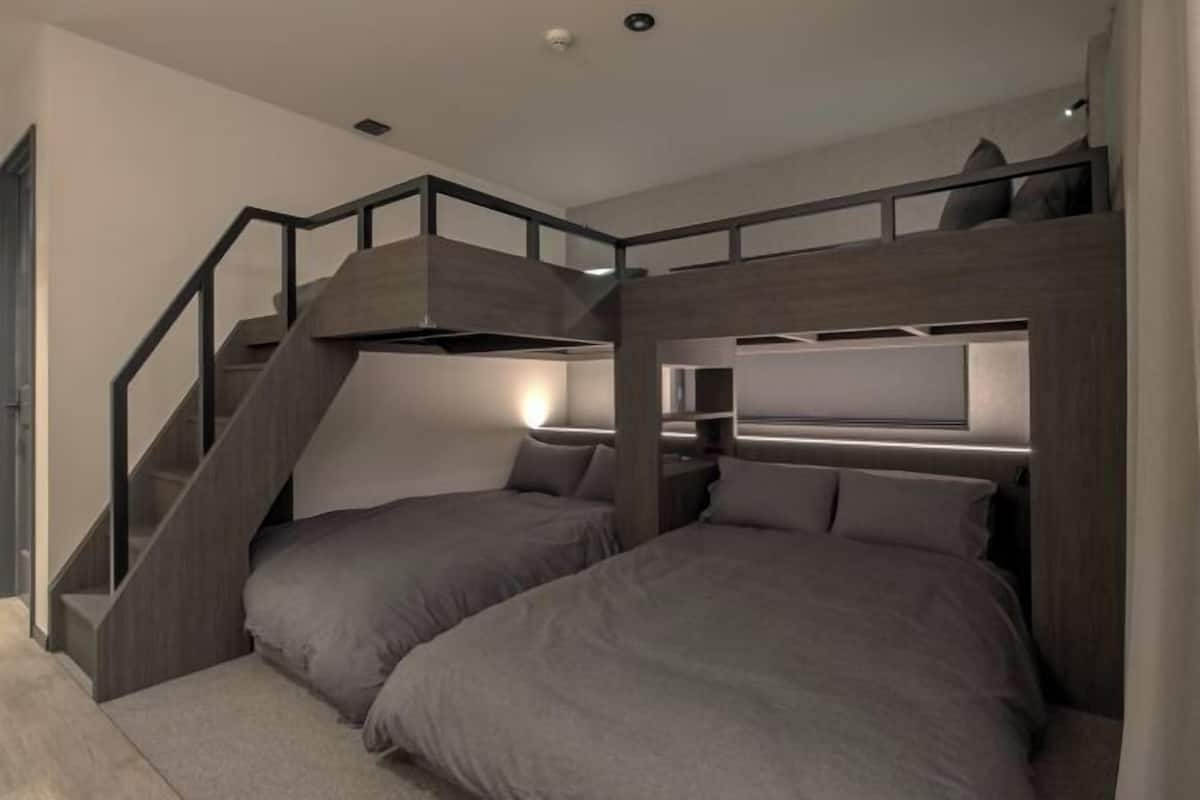 A modern room with bunk beds, a staircase, and built-in shelves.
