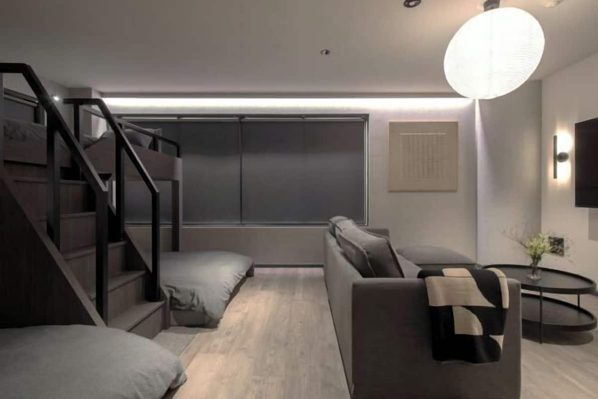 A modern room with a staircase, a sofa, a small table, and a wall-mounted TV.