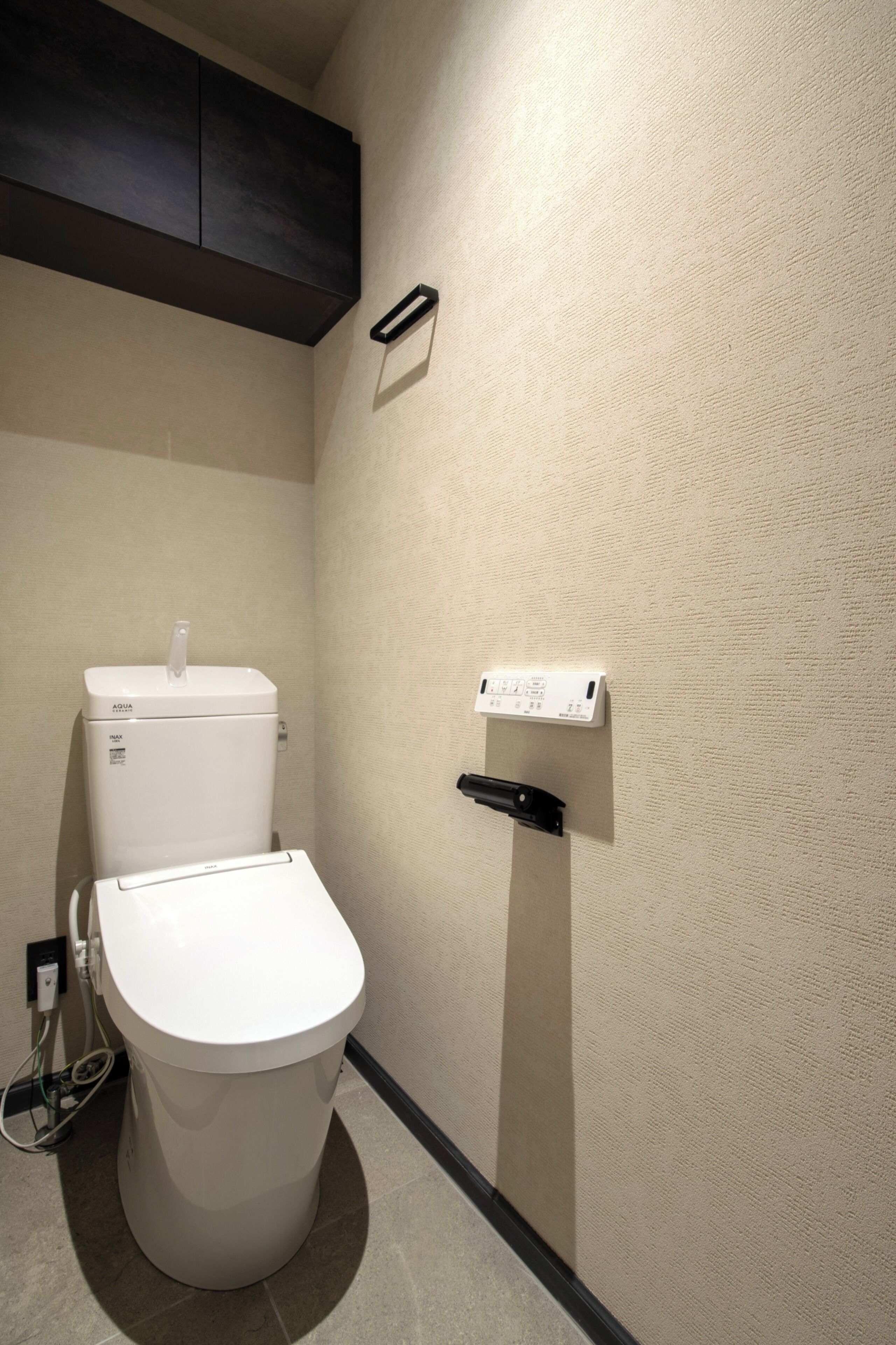 A bathroom with a toilet, a water heater, and a wall-mounted towel rack.
