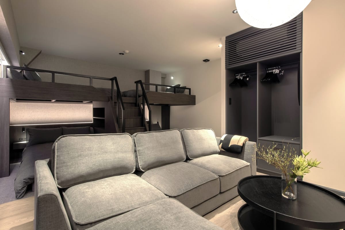 A modern living room with a sofa, a small table with a vase, and a staircase leading to an upper level.
