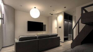 Un salon moderne avec un canapé, un téléviseur à écran plat, un éclairage encastré et un escalier.