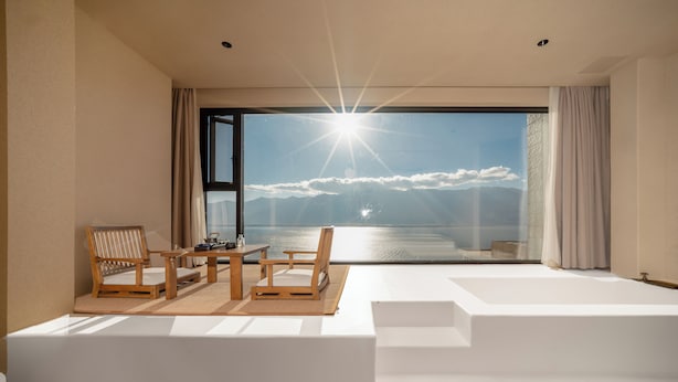 A modern room with a large window, a wooden table, two chairs, and a white sofa. - Muyi Seaview Holiday Homestay (Dali)