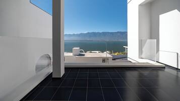 A modern room with a large window offering a view of a mountainous landscape and a body of water.