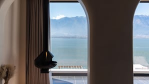 A room with a large window overlooking a body of water and mountains. - Muyi Seaview Holiday Homestay (Dali)