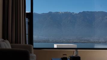 A room with a large window overlooking a mountain range and a cityscape.