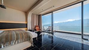 A modern hotel room with a large bed, a view of the sea, and a balcony with outdoor furniture. - Muyi Seaview Holiday Homestay (Dali)