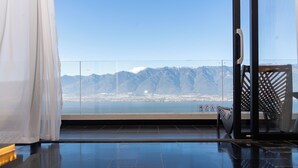 A modern room with a large glass door leading to a balcony with a mountain view. - Muyi Seaview Holiday Homestay (Dali)